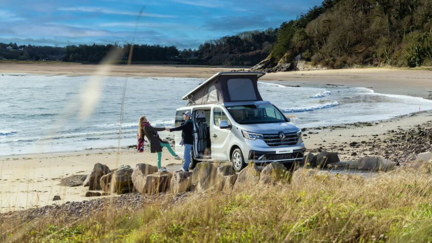 Photo d'un Van au bord de la mer avec un jeune couple au bord du van. Sur la photo, il y a un texte en grand indiquant "VANLIFE" pour illustrer la publicité Antilope Van du Garage Daniel